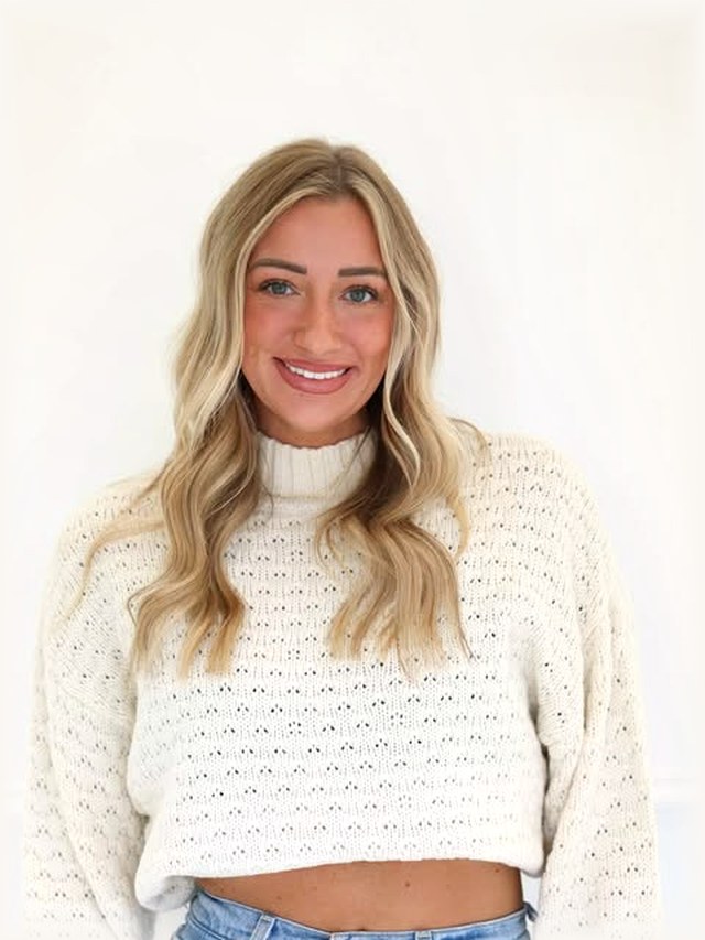 Samantha, co-owner, photographed in a cream knit against the salon&rsquo;s white studio wall.