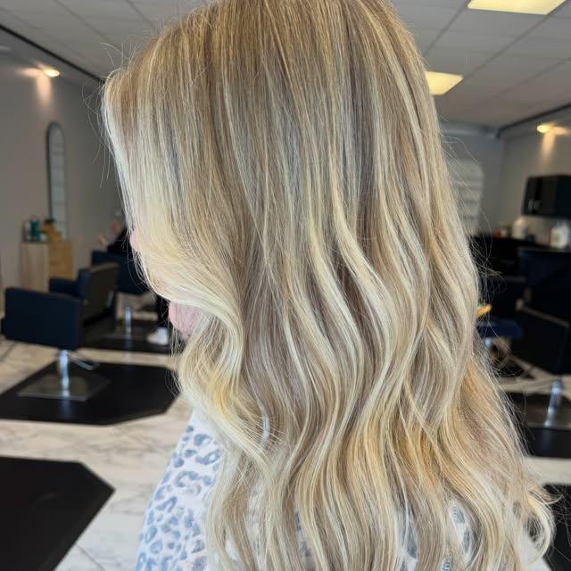 Long golden-blonde balayage with a soft root, waved to the ends.