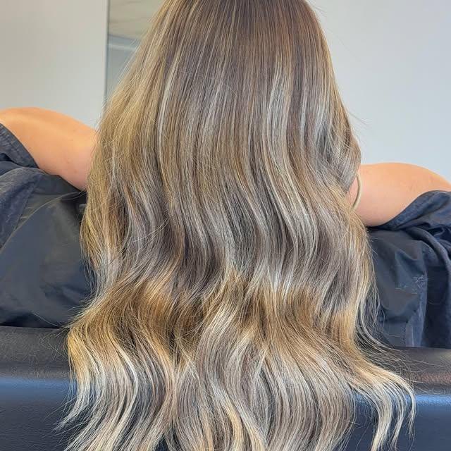 Long bronde balayage seen from behind, cool ribbons through a warm base.