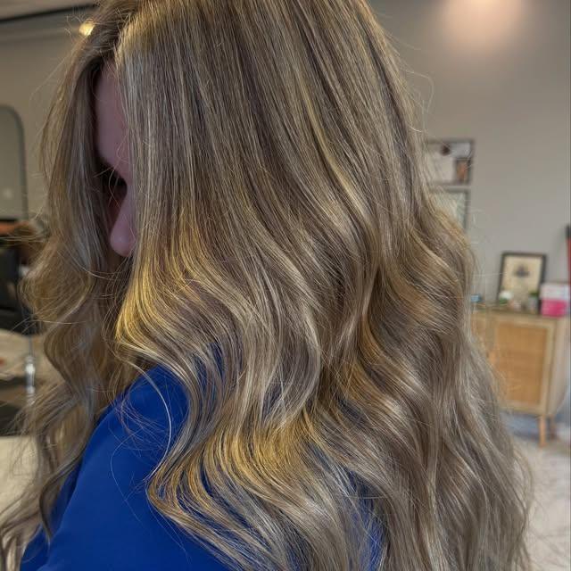Soft beige-blonde with fine highlights, shown from the side in loose waves.