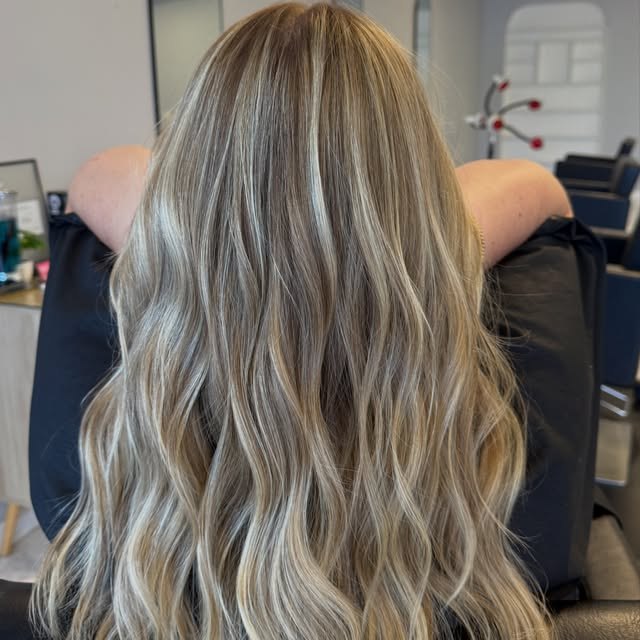 Dimensional blonde highlights over a deeper root, long and waved.